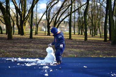 İlkbaharda şehir parkında çocukların parkındaki son kardan adam yapan çocuk. Çocuk ve üzgün görünümlü kardan adam kışın bitmesini bekliyor..
