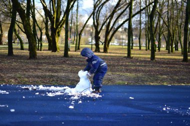 İlkbaharda şehir parkında çocukların parkındaki son kardan adam yapan çocuk. Çocuk ve üzgün görünümlü kardan adam kışın bitmesini bekliyor..