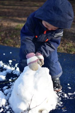 İlkbaharda şehir parkında çocukların parkındaki son kardan adam yapan çocuk. Çocuk ve üzgün görünümlü kardan adam kışın bitmesini bekliyor..