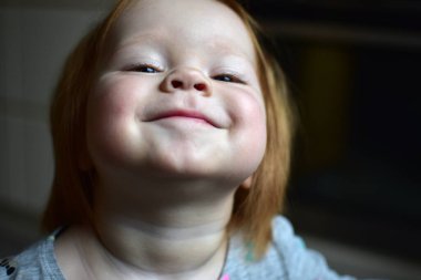 Kızıl, dağınık saçlı, yeni yürümeye başlayan kız, tuhaf bir şekilde yukarı bakıyor. Kızın sabırsız bir şekilde ilgi bekliyor. En üstten çocuk görünümü.