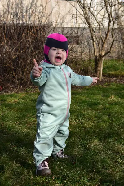 Bebek kız dışarıda ağzı açık duruyor ve baharda ellerini havaya kaldırdı. Küçük kız baharda dışarıda sanatsal bir kavram konuşuyor..