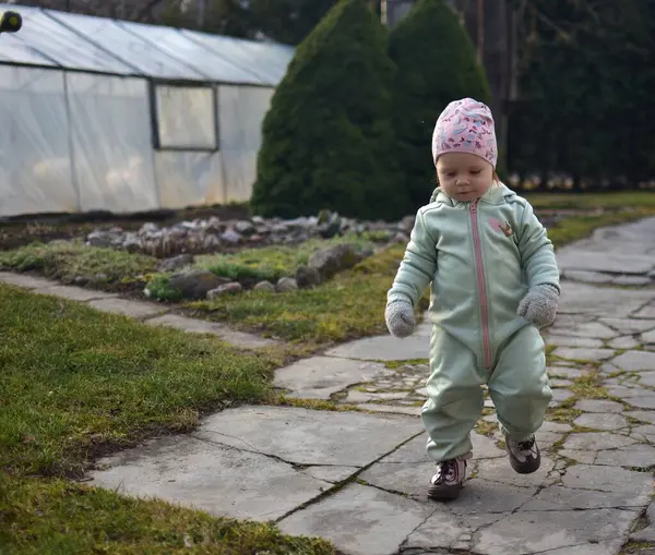Nane kokulu, yumuşak kabuklu bebek baharda arka bahçede oynuyor. Yürüyen küçük kız beton patikada yürüyordu..
