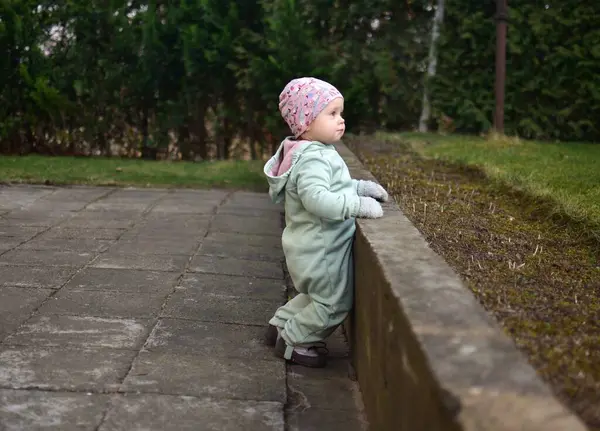Nane kokulu, yumuşak kabuklu bebek baharda arka bahçede oynuyor. Küçük kız fayansların üzerinde yürüyor..