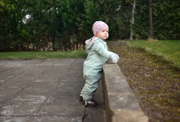 Nane kokulu, yumuşak kabuklu bebek baharda arka bahçede oynuyor. Küçük kız fayansların üzerinde yürüyor..