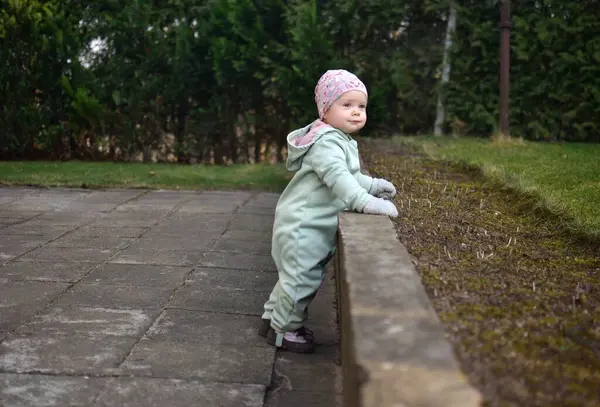 Nane kokulu, yumuşak kabuklu bebek baharda arka bahçede oynuyor. Küçük kız fayansların üzerinde yürüyor..