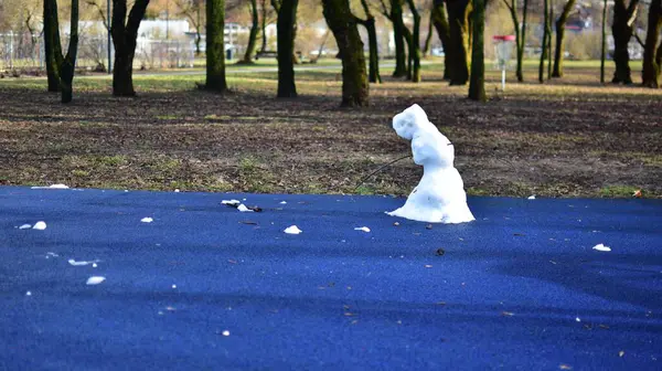 Baharda şehir parkındaki çocuk parkında neredeyse eriyen kardan adam. Üzgün bakışlı kardan adam kışın bitmesini bekliyor..