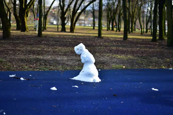 Baharda şehir parkındaki çocuk parkında neredeyse eriyen kardan adam. Üzgün bakışlı kardan adam kışın bitmesini bekliyor..