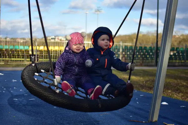 Erkek ve kız kardeş şehir parkında birlikte sallanıyorlar. İki kardeş arasındaki güçlü bağ kavramı. Erkek kardeşi küçük kız kardeşine sarılıyor. Kardeşlerin sevgisi..