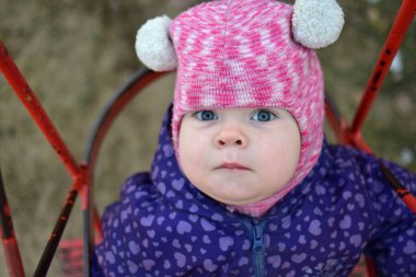 Soğuk havada sovyet tarzı çocuk parkında sallanan küçük bir kız çocuğu. Küçük kız kışın halk parkında eğleniyor.