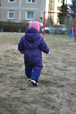 Sovyet tarzında oynayan küçük bir kız çocuğu soğuk havada çocuk parkında oynuyor. Küçük kız kışın halk parkında eğleniyor..