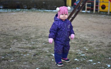 Sovyet tarzında oynayan küçük bir kız çocuğu soğuk havada çocuk parkında oynuyor. Küçük kız kışın halk parkında eğleniyor..