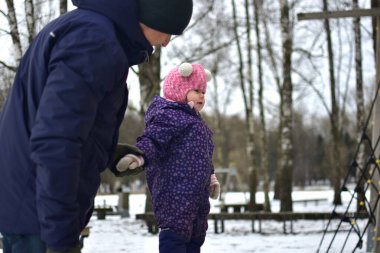 Babası küçük kızıyla şehir parkında soğuk kış mevsiminde oynuyor. Baba ve kızı birlikte vakit geçiriyorlar. Babam küçük kızlarının elini tutuyor..