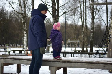 Babası küçük kızıyla şehir parkında soğuk kış mevsiminde oynuyor. Baba ve kızı birlikte vakit geçiriyorlar. Babam küçük kızlarının elini tutuyor..