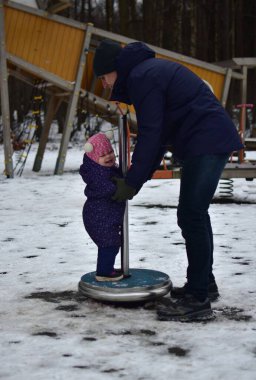 Babası küçük kızıyla şehir parkında soğuk kış mevsiminde oynuyor. Baba ve kızı birlikte vakit geçiriyorlar. Babası küçük kızını döner oyuncakla tutuyor..
