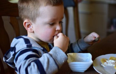 Küçük çocuk kahvaltıda gözleme yiyor evde. Çocuk lezzetli yemek yiyor..