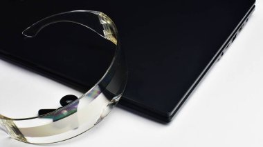 Beyaz arka planda sanal gerçeklik gözlüklü ve kulaklık takan bir laptop. Geleceğin teknolojileri burada. Dizüstü bilgisayarda yakın görüntüde sanal gerçeklik gözlükleri.