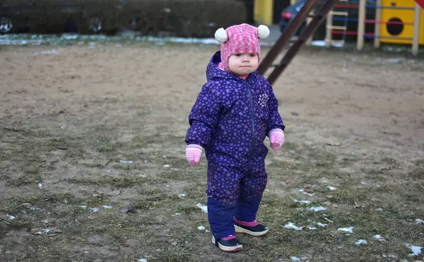 Sovyet tarzında oynayan küçük bir kız çocuğu soğuk havada çocuk parkında oynuyor. Küçük kız kışın halk parkında eğleniyor..