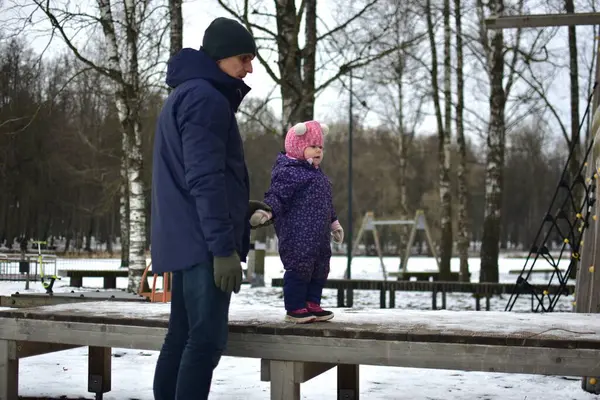 Babası küçük kızıyla şehir parkında soğuk kış mevsiminde oynuyor. Baba ve kızı birlikte vakit geçiriyorlar. Babam küçük kızlarının elini tutuyor..