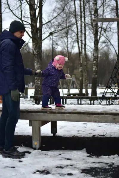 Babası küçük kızıyla şehir parkında soğuk kış mevsiminde oynuyor. Baba ve kızı birlikte vakit geçiriyorlar. Babam küçük kızlarının elini tutuyor..