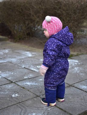 Küçük kız doğu Avrupa 'da soğuk kış mevsiminde kış kıyafetleriyle dışarıda dikiliyor..