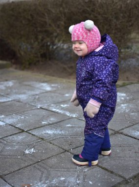 Küçük kız doğu Avrupa 'da soğuk kış mevsiminde kış kıyafetleriyle dışarıda dikiliyor..