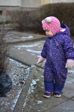Doğu Avrupa 'da soğuk kış mevsiminde çöp torbasının yanında duran küçük kız. Küçük kız yere düşen çöp torbasını araştırıyor..