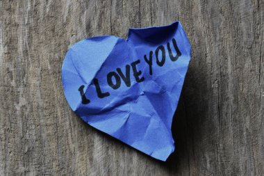 Tahta desenli arka planda sevgililer günü için buruşuk mavi kalp şeklinde kağıt üzerinde seni seviyorum mesajı. Kırık Sevgililer Günü kartında seni seviyorum yazıyor. Reddedilmiş sevgililer günü tebrikleri..