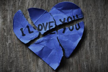 Ahşap zemin üzerinde sevgililer günü için buruşuk çizik mavi kalp şeklindeki bir kartta seni seviyorum mesajı. Kırık Sevgililer Günü kartında seni seviyorum yazıyor. Reddedildi. Seni sevmiyorum..