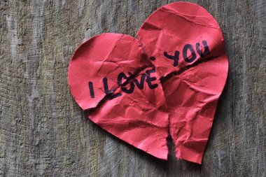 Tahta arka planda sevgililer günü için buruşuk, harap olmuş kırmızı kalp şeklindeki bir kartta seni seviyorum mesajı. Kırık Sevgililer Günü kartında seni seviyorum yazıyor. Reddedildi. Seni sevmiyorum..