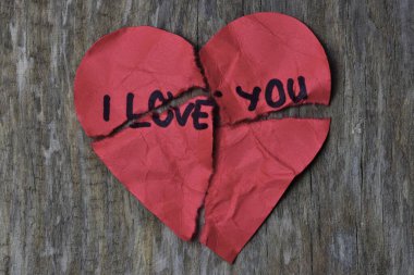Tahta arka planda sevgililer günü için buruşuk, harap olmuş kırmızı kalp şeklindeki bir kartta seni seviyorum mesajı. Kırık Sevgililer Günü kartında seni seviyorum yazıyor. Reddedildi. Seni sevmiyorum..