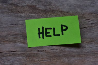 Tahta döşemeli arka plandaki yeşil yapışkan nota mesaj yardımı. Siyah kalem not kağıdına kelime yardımı yazdı.