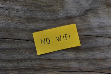 Tahta kaplamalı arka planda sarı yapışkan notta kablosuz internet yok. Not kağıdına Wi-Fi yazmayan bir kalem..