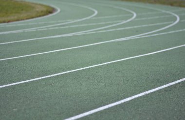 Yeşil koşu yolu eğrisi, beyaz çizgiler ve yeşil çimenler
