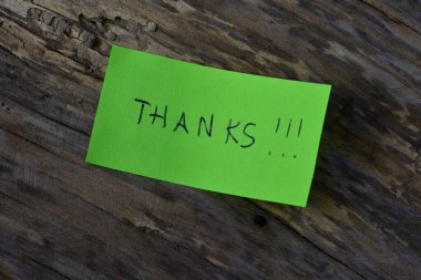 Tahta döşemeli arka planda yeşil yapışkan not günü için teşekkür ederim.