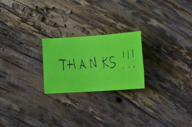 Tahta döşemeli arka planda yeşil yapışkan not günü için teşekkür ederim.