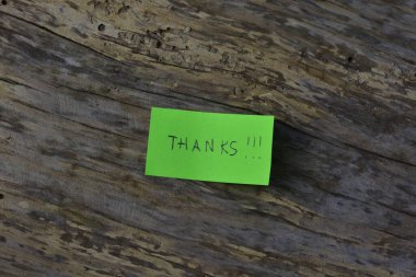 Tahta döşemeli arka planda yeşil yapışkan not günü için teşekkür ederim.