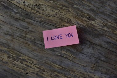 Tahta döşemeli arka planda sevgililer günü için pembe yapışkan notta seni sevdiğimi söyle.