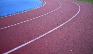 Sol tarafta mavi spor sahası olan kırmızı koşu pisti.