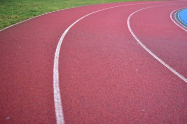 Sol tarafında yeşil çimen olan kırmızı koşu yolu eğrisi.