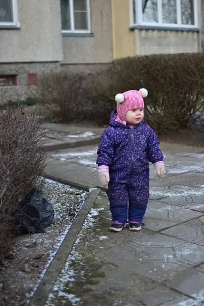 Doğu Avrupa 'da soğuk kış mevsiminde çöp torbasının yanında duran küçük kız. Küçük kız yere düşen çöp torbasını araştırıyor..