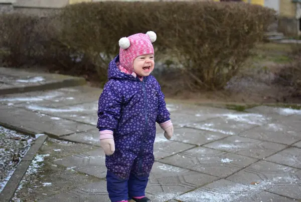 Apartman girişinin yanında duran küçük kız. Doğu Avrupa 'da kış mevsiminde kışlık kıyafetlerle bağırıyor..