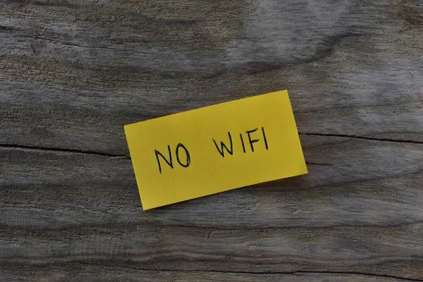 Tahta kaplamalı arka planda sarı yapışkan notta kablosuz internet yok. Not kağıdına Wi-Fi yazmayan bir kalem..