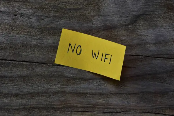 Tahta kaplamalı arka planda sarı yapışkan notta kablosuz internet yok. Not kağıdına Wi-Fi yazmayan bir kalem..
