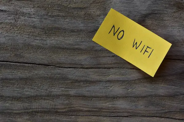 Tahta kaplamalı arka planda sarı yapışkan notta kablosuz internet yok. Not kağıdına Wi-Fi yazmayan bir kalem..