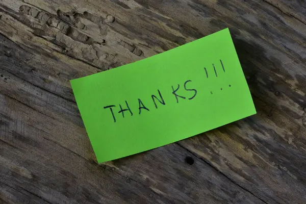 Tahta döşemeli arka planda yeşil yapışkan not günü için teşekkür ederim.