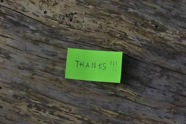 Tahta döşemeli arka planda yeşil yapışkan not günü için teşekkür ederim.