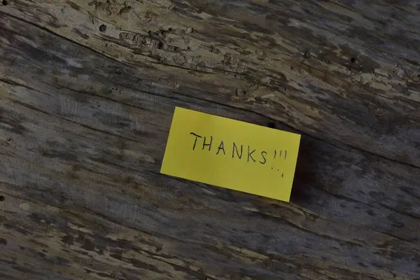 Tahta döşemeli arka planda sarı yapışkan not gününde teşekkür ederim.