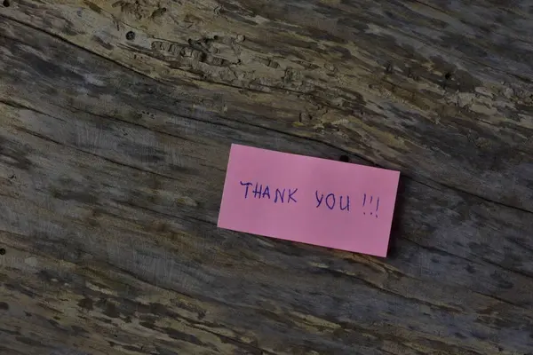 Tahta döşemeli arka planda pembe yapışkan not gününde teşekkür ederim.