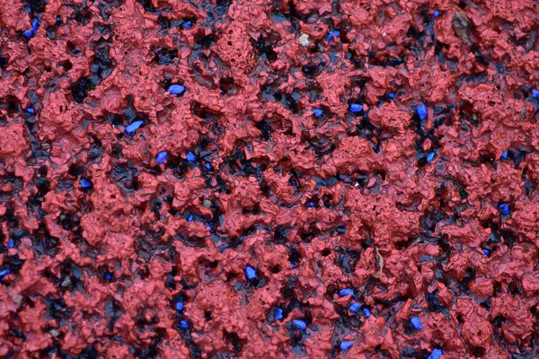 Kırmızı spor alanı lastik kaplaması makro manzarayı kapatıyor. Oyun alanı kaldırım döşemesi dokusu son derece yakın.