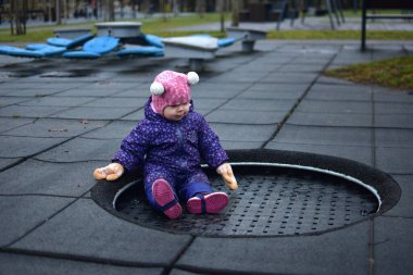 Küçük kız, soğuk kış zamanı halk parkında trambolinde oynuyor. Bebeğim sonbaharda trambolinde eğleniyor.